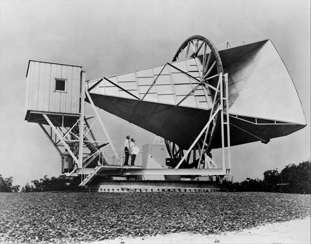 Título: A antena de chifre de Holmdel usada por Arno Penzias e Robert Wilson - Descrição: Fotografia em preto e branco da grande antena de chifre de Holmdel montada sobre uma base giratória.