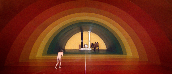 Título: cannes-69398 - Descrição: A lone figure approaching a rainbow-shaped ceremonial chamber