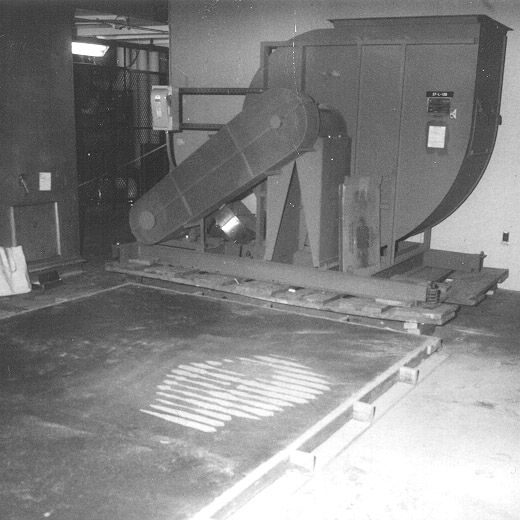 The striped PJW face stenciled onto freshly poured cement next to industrial machinery, before it was covered up