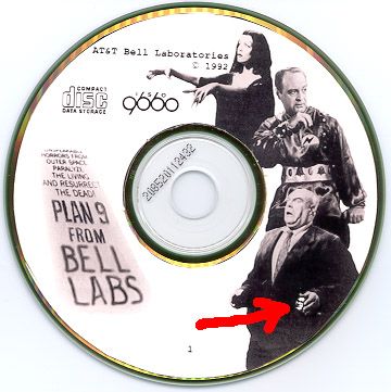 The original Plan 9 from Bell Labs CD with movie characters printed on it and a red arrow pointing to a tiny PJW face one of them is holding