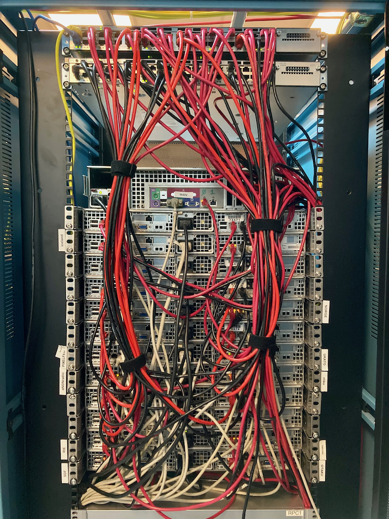 The back of SDF's server rack in 2021, full of red and white network cables